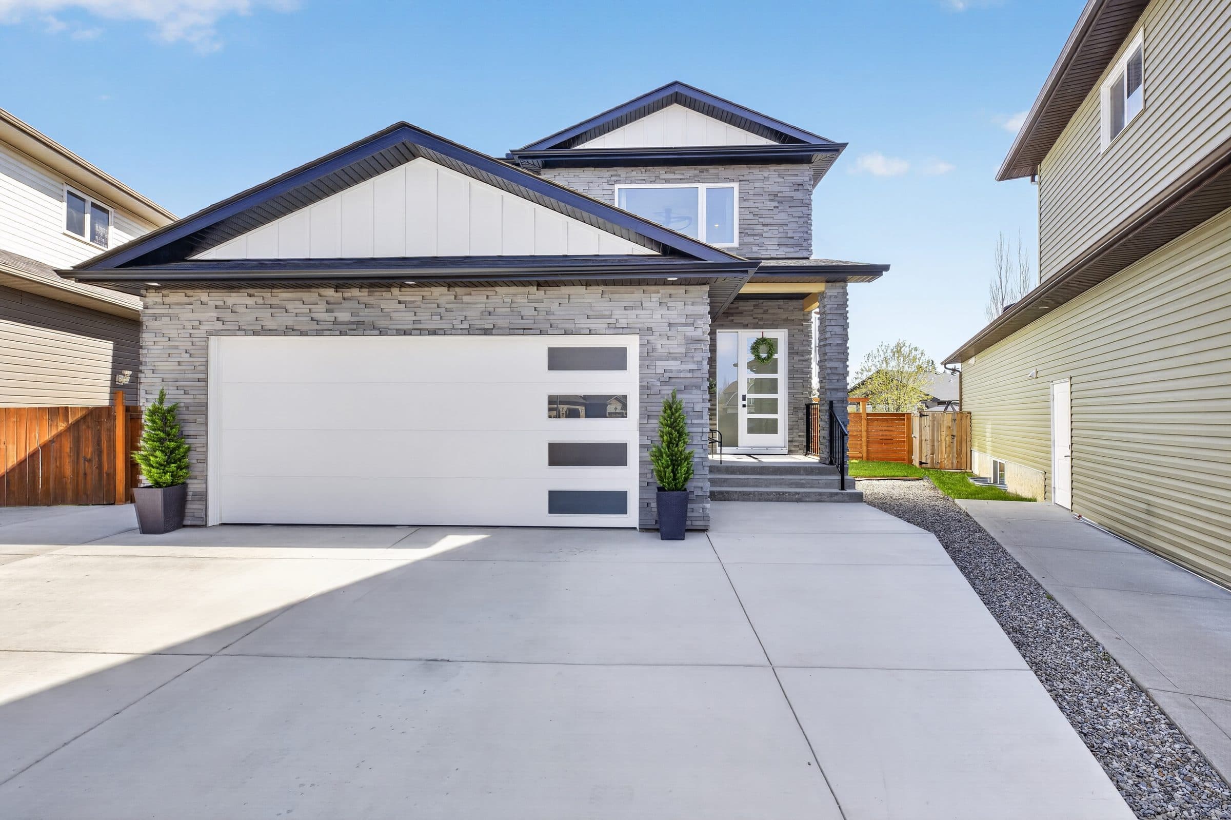 Front of a white and grey stone two-storey home with a single garage
