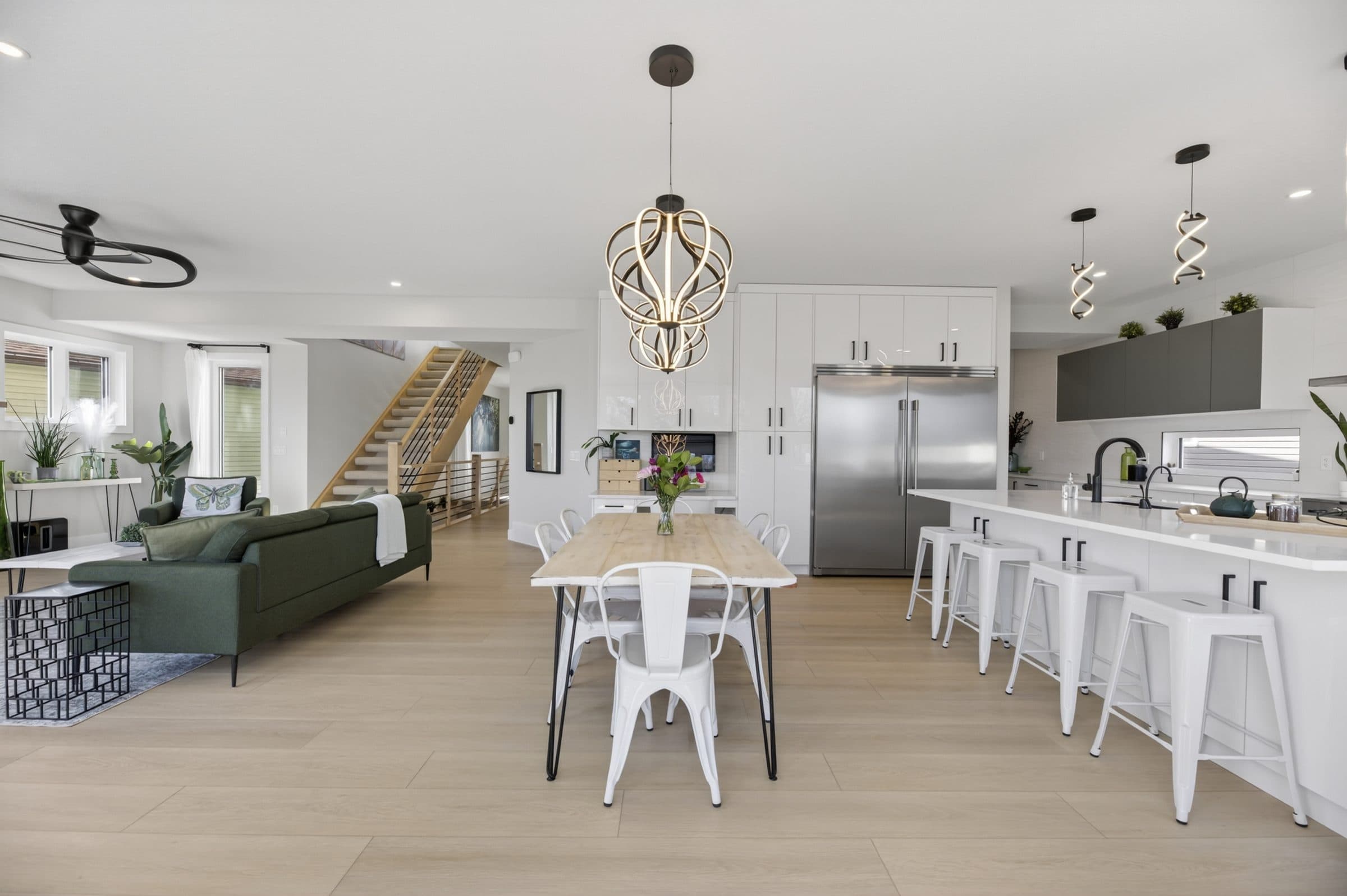 Open great room with living area, dining table, kitchen and staircase